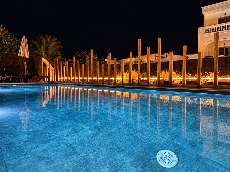 Pool at night with the lit wooden posts – Dragonfly Villas, Santorini